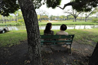 Doğu Asyalı çift parkta oturuyor ve dinleniyorlar..
