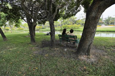 Doğu Asyalı çift parkta oturuyor ve dinleniyorlar..