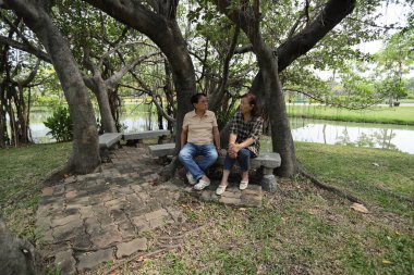 Doğu Asyalı çift parkta oturuyor ve dinleniyorlar..