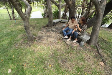 Doğu Asyalı çift parkta oturuyor ve dinleniyorlar..