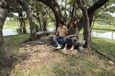 Doğu Asyalı çift parkta oturuyor ve dinleniyorlar..