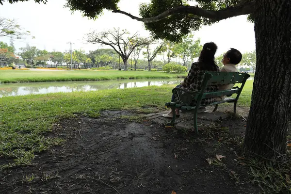 Doğu Asyalı çift parkta oturuyor ve dinleniyorlar..