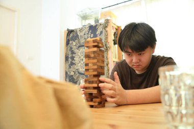Güneydoğu Asyalı çocuk annesiyle tahta kule oyunu oynuyor..