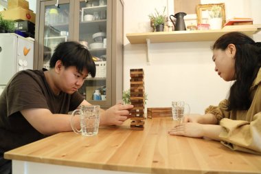 Güneydoğu Asyalı çocuk annesiyle tahta kule oyunu oynuyor..