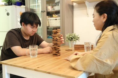 Güneydoğu Asyalı çocuk annesiyle tahta kule oyunu oynuyor..