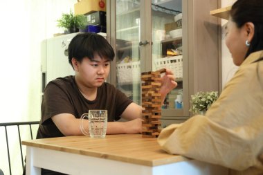 Güneydoğu Asyalı çocuk annesiyle tahta kule oyunu oynuyor..