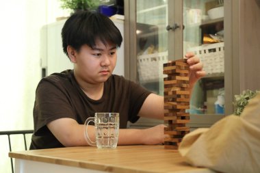 Güneydoğu Asyalı çocuk annesiyle tahta kule oyunu oynuyor..