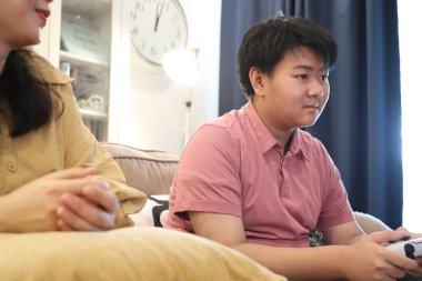 Güneydoğu Asya 'lı bekar anne, genç oğlunun televizyonda oyun oynamasını izliyor..