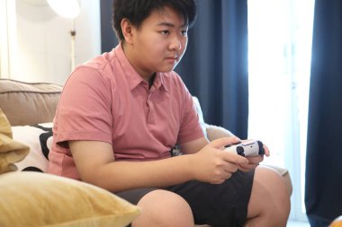 Güneydoğu Asya 'lı bekar anne, genç oğlunun televizyonda oyun oynamasını izliyor..