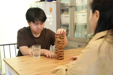 Güneydoğu Asyalı çocuk annesiyle tahta kule oyunu oynuyor..