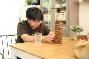 Güneydoğu Asyalı çocuk annesiyle tahta kule oyunu oynuyor..