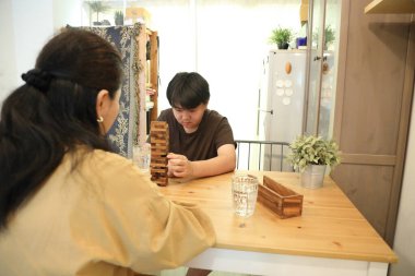 Güneydoğu Asyalı çocuk annesiyle tahta kule oyunu oynuyor..