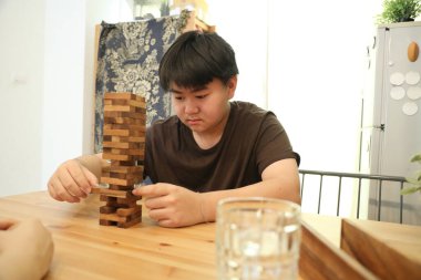 Güneydoğu Asyalı çocuk annesiyle tahta kule oyunu oynuyor..