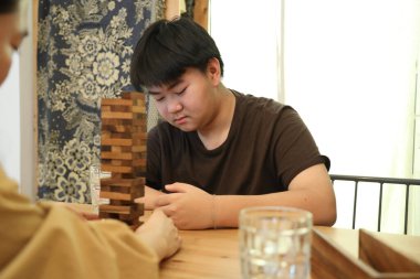 Güneydoğu Asyalı çocuk annesiyle tahta kule oyunu oynuyor..