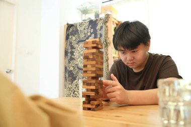 Güneydoğu Asyalı çocuk annesiyle tahta kule oyunu oynuyor..