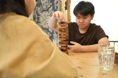 Güneydoğu Asyalı çocuk annesiyle tahta kule oyunu oynuyor..