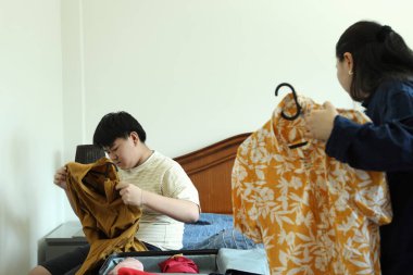 Güneydoğu Asya 'lı bekar anne, genç oğlunun bavullarını toplamasına yardım ediyor..