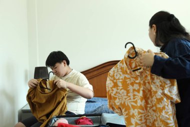 Güneydoğu Asya 'lı bekar anne, genç oğlunun bavullarını toplamasına yardım ediyor..