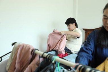 Güneydoğu Asya 'lı bekar anne, genç oğlunun bavullarını toplamasına yardım ediyor..