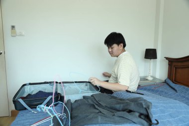 Güneydoğu Asya 'lı bekar anne, genç oğlunun bavullarını toplamasına yardım ediyor..