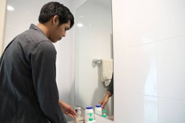 Güneydoğu Asyalı adam yüzünü yıkıyor ve saçını banyoda şekillendiriyor..
