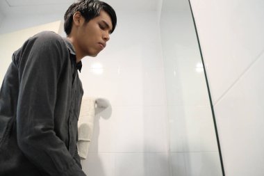 Güneydoğu Asyalı adam yüzünü yıkıyor ve saçını banyoda şekillendiriyor..