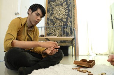 Güneydoğu Asyalı adam arkadaşlarıyla domino oynuyor..