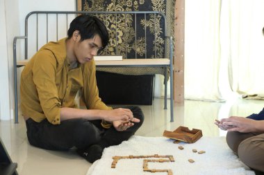 Güneydoğu Asyalı adam arkadaşlarıyla domino oynuyor..