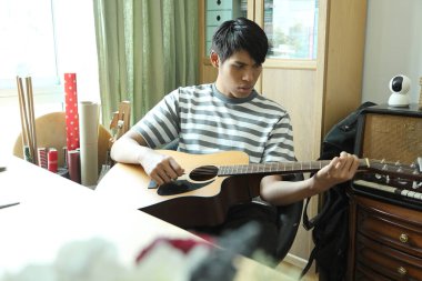 Güneydoğu Asyalı adam ilk defa internetten gitar çalmayı öğreniyor.