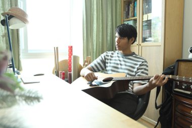 Güneydoğu Asyalı adam ilk defa internetten gitar çalmayı öğreniyor.