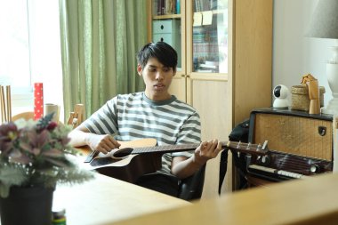 Güneydoğu Asyalı adam ilk defa internetten gitar çalmayı öğreniyor.