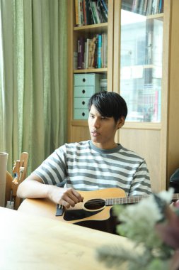 Güneydoğu Asyalı adam ilk defa internetten gitar çalmayı öğreniyor.