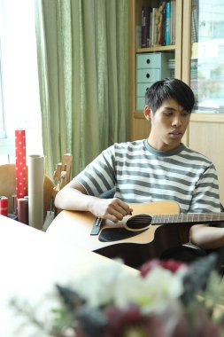 Güneydoğu Asyalı adam ilk defa internetten gitar çalmayı öğreniyor.