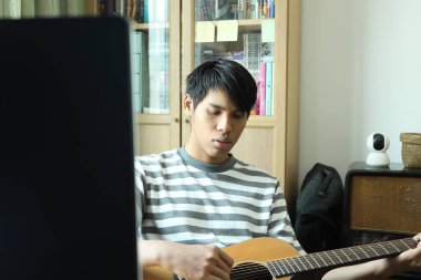 Güneydoğu Asyalı adam ilk defa internetten gitar çalmayı öğreniyor.