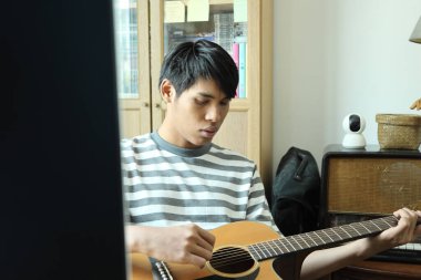 Güneydoğu Asyalı adam ilk defa internetten gitar çalmayı öğreniyor.