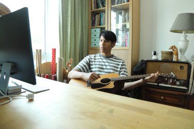 Güneydoğu Asyalı adam ilk defa internetten gitar çalmayı öğreniyor.