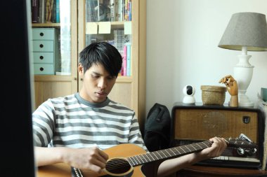 Güneydoğu Asyalı adam ilk defa internetten gitar çalmayı öğreniyor.