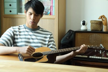 Güneydoğu Asyalı adam ilk defa internetten gitar çalmayı öğreniyor.