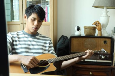 Güneydoğu Asyalı adam ilk defa internetten gitar çalmayı öğreniyor.