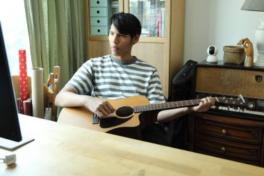 Güneydoğu Asyalı adam ilk defa internetten gitar çalmayı öğreniyor.