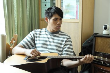 Güneydoğu Asyalı adam ilk defa internetten gitar çalmayı öğreniyor.