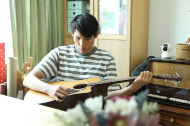 Güneydoğu Asyalı adam ilk defa internetten gitar çalmayı öğreniyor.