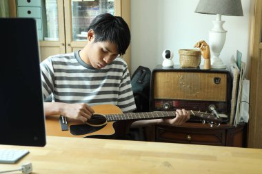 Güneydoğu Asyalı adam ilk defa internetten gitar çalmayı öğreniyor.