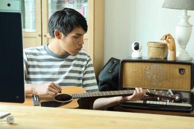 Güneydoğu Asyalı adam ilk defa internetten gitar çalmayı öğreniyor.