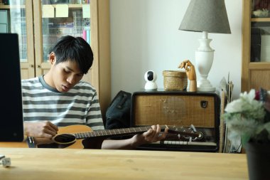 Güneydoğu Asyalı adam ilk defa internetten gitar çalmayı öğreniyor.