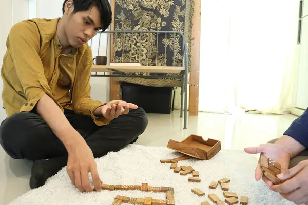 Güneydoğu Asyalı adam arkadaşlarıyla domino oynuyor..