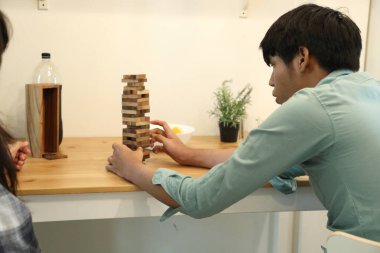 Güneydoğu Asyalı adam arkadaşlarıyla Jenga masa oyunu oynuyor...