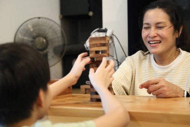 Güneydoğu Asyalı çocuk annesiyle tahta kule oyunu oynuyor..