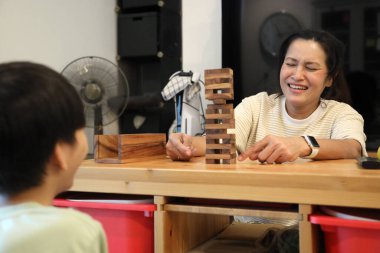 Güneydoğu Asyalı çocuk annesiyle tahta kule oyunu oynuyor..