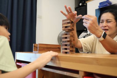 Güneydoğu Asyalı çocuk annesiyle tahta kule oyunu oynuyor..